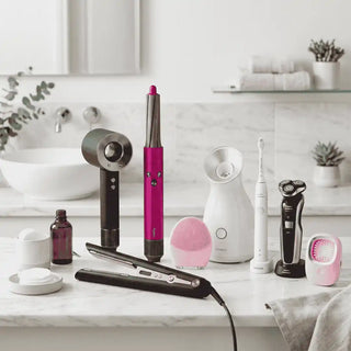 Gama de eletrodomésticos para beleza e cuidado pessoal sobre bancada de mármore, incluindo secador de cabelo de alta tecnologia, alisador, máscara LED facial, escova de limpeza facial sónica, máquina de barbear elétrica e escova de dentes elétrica